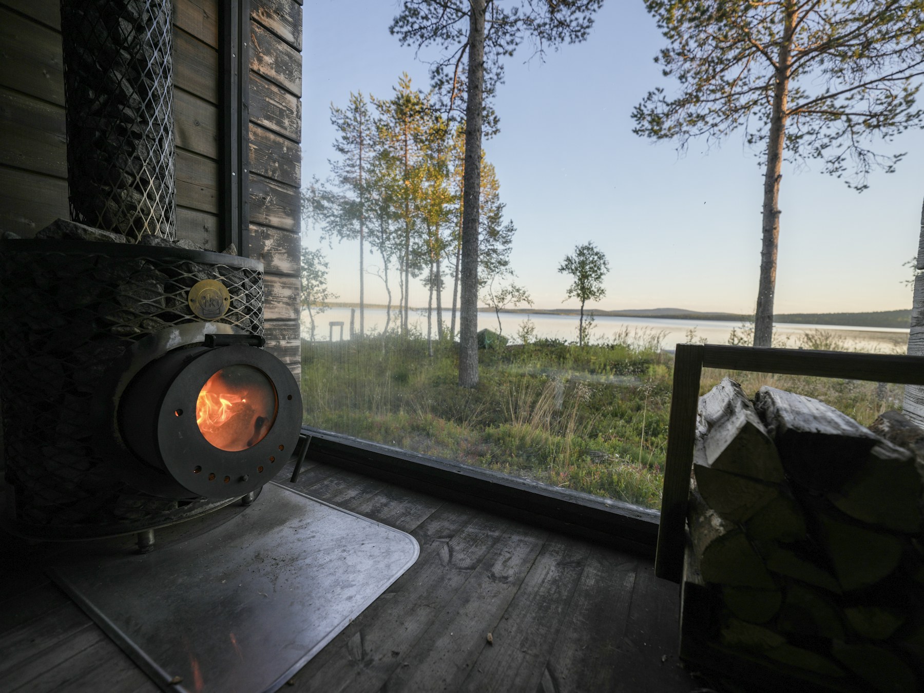 Blick aus einer Sauna auf einen See im Abendlicht in Muonio, Finnland