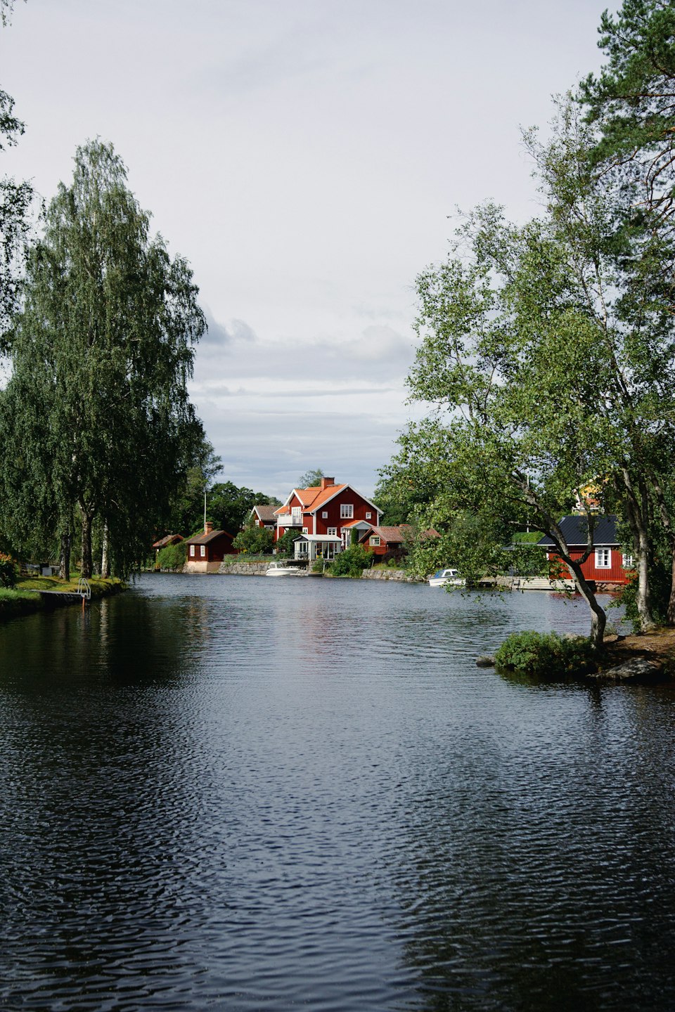 Rote Häuser und Bäume am Wasser in Sundborn, Schweden