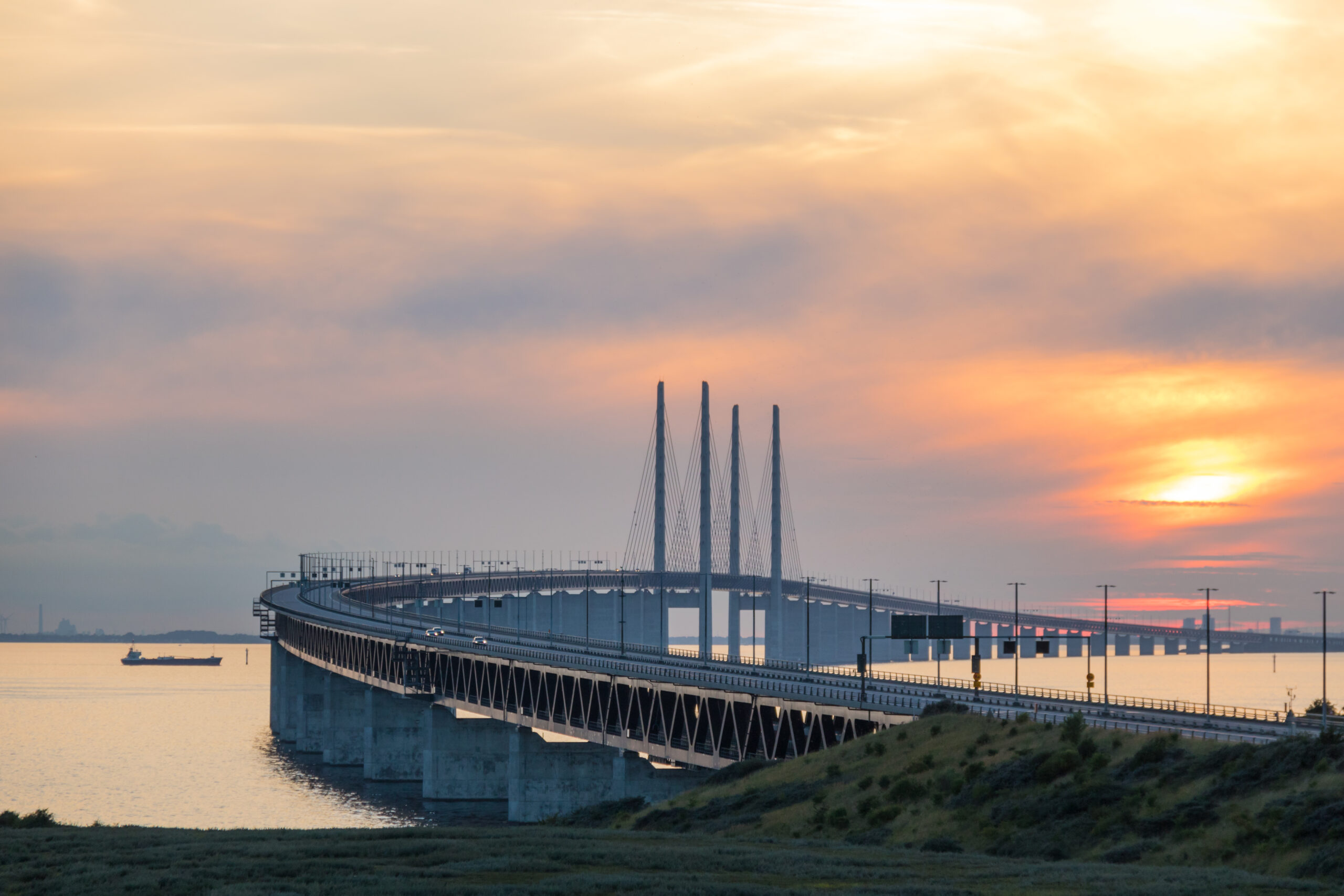 Öresundbrücke mit markanten Schrägseilpfeilern und kurviger Fahrbahn über dem Meer bei Sonnenuntergang